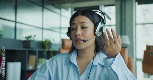 A highly focused woman wearing a headset actively engages with clients in a modern and sleek office space