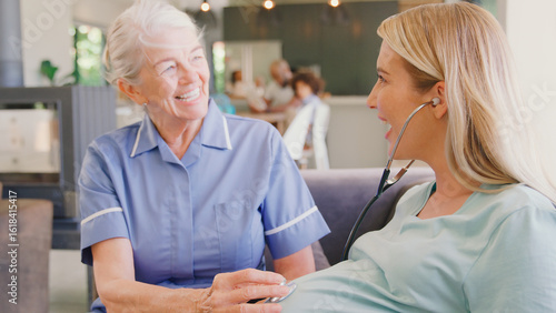 Wallpaper Mural Senior Midwife With Stethoscope Visiting Pregnant Woman At Home With Family In Background Torontodigital.ca