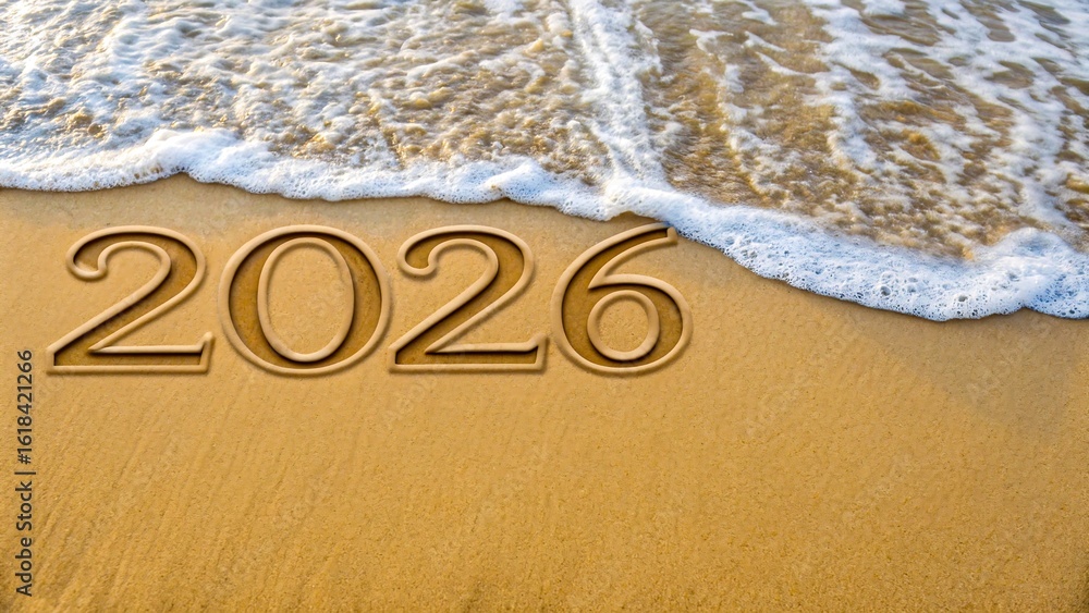Fototapeta premium Year 2026 written on beach sand with ocean wave approaching for future and time concept