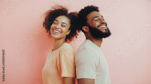 Couple Poses Joyfully Against a Soft Pink Background During a Cheerful Moment...