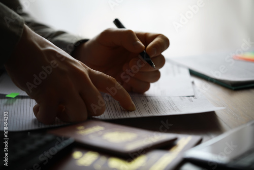 Wallpaper Mural Hands Filling Out Tax Forms With Passport Documents in Professional Office Setting Torontodigital.ca