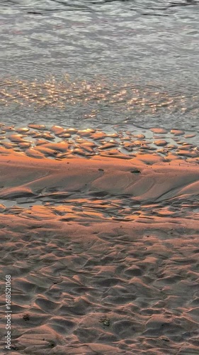 Pattern of rippled sands at the beach. Golden light reflected on the wet sand making a beautiful texture pattern