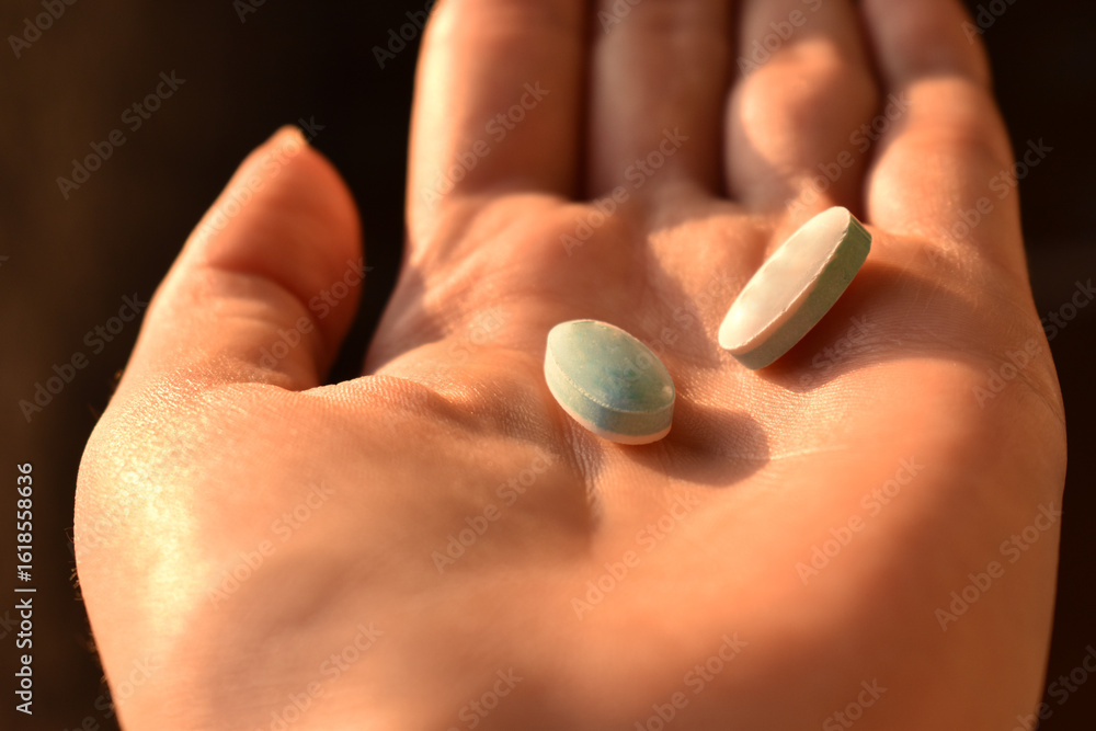 Close-up of a woman holding two pills in her palm. Medical and pharmaceutical concept. Close-up of a woman holding two pills in her palm. Medical and pharmaceutical concept.
