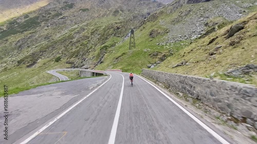 Epic cycling scene on Transfagarasan Highway in Romania. Cyclist rides through breathtaking mountain landscape with sharp turns and stunning views. Perfect for travel, sports, and adventure projects.