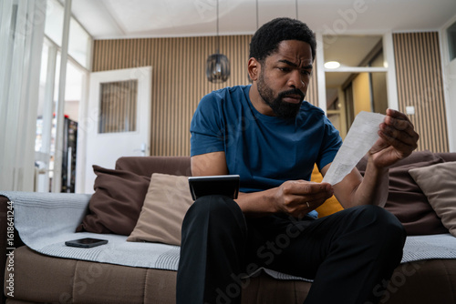 Fototapet Worried young black man at home feeling stressed about cost of living, rent and