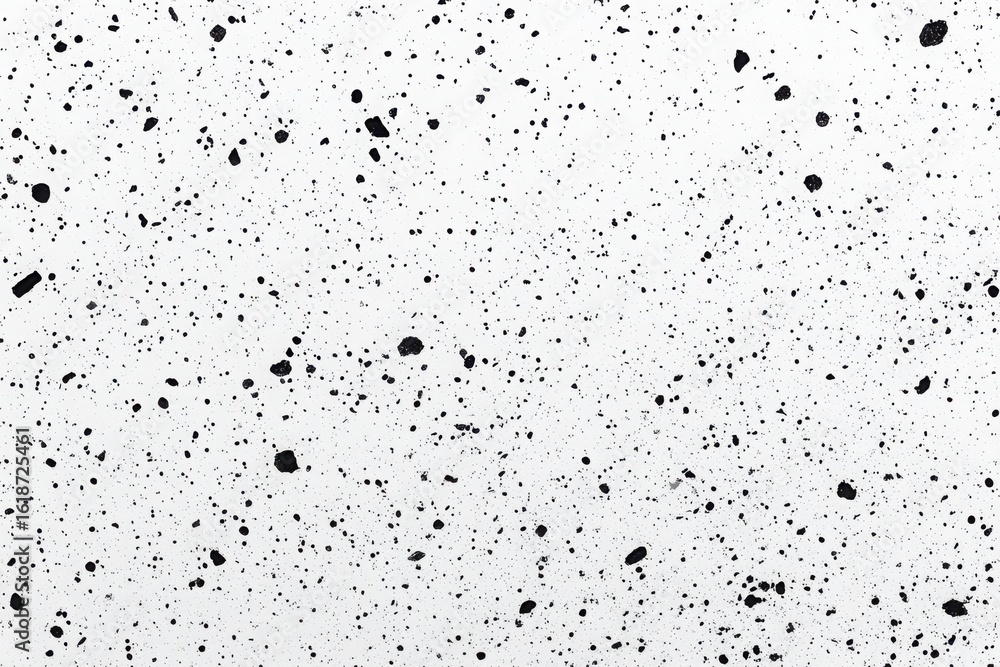 A white surface with many black spots of varying sizes randomly scattered across the entire background A white surface with many black spots of varying sizes randomly scattered across the entire background