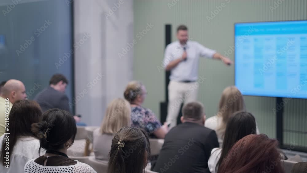 Audience attentively listens to a speaker giving a presentation during a business conference.