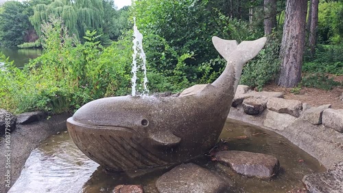 Smiling statue and whale fountain sprays Water from its hole on head back