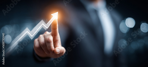 Businessman touching a glowing upward arrow graph symbolizing business growth, success, and financial progress

