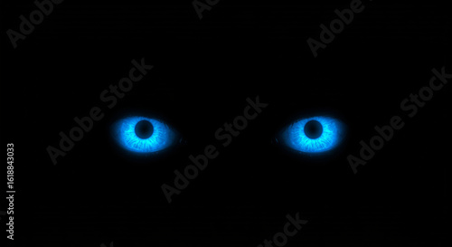 Glowing blue eyes in the dark spooky mystery concept for halloween and scary night scenes design element on dark background
