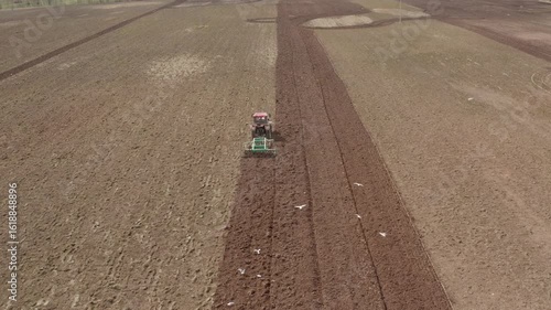 Aerial of a tractor with a grain seeder works in the field