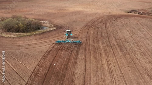 A tractor with a grain seeder is working in the field