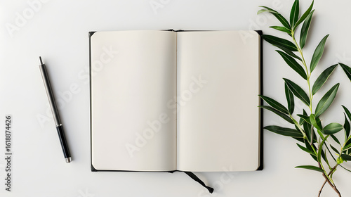 Flat lay of a blank open notebook with a pen and a green branch on a white background, a concept of creativity and journaling.
