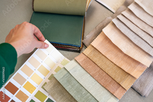 Top view of Interior designer choosing materials for home renovation. Woman matching samples the color of the walls to the parquet board, fabrics swatches. House decoration renovation