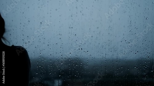 Sad woman silhouette looking out rainy window for mood background or depression concept stock footage video 4k