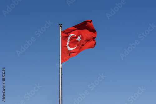 Turkish flag waving in blue sky.