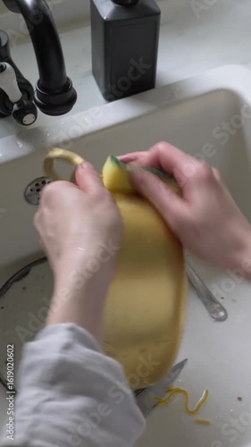 Vertical Video of Girl Washing Yellow Aluminum Pot at Kitchen Sink at Home