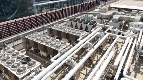 Aerial drone view of industrial HVAC systems, air conditioning units, ventilation fans, and piping on the rooftop 

