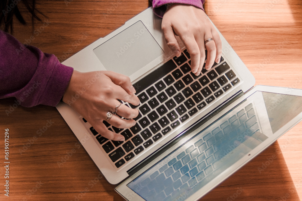 Fototapeta premium Young woman wearing a purple sweater using her computer for study at her desk. Remote work.