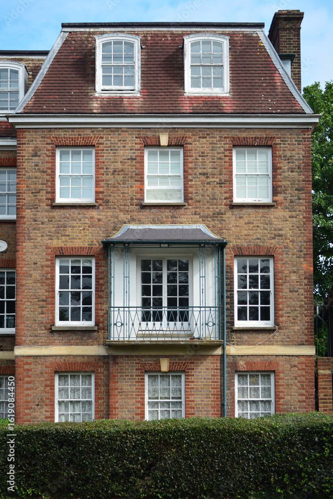 The brick building features a charming balcony and multiple windows, highlighting the architectural style of the area. Lush greenery surrounds the residence, creating a peaceful urban setting The brick building features a charming balcony and multiple windows, highlighting the architectural style of the area. Lush greenery surrounds the residence, creating a peaceful urban setting