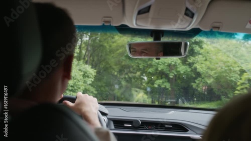 Wallpaper Mural Front window of car with reflection of male driver face in rectangular mirror and long country road surrounded by green trees during movement of vehicle driven by man Torontodigital.ca