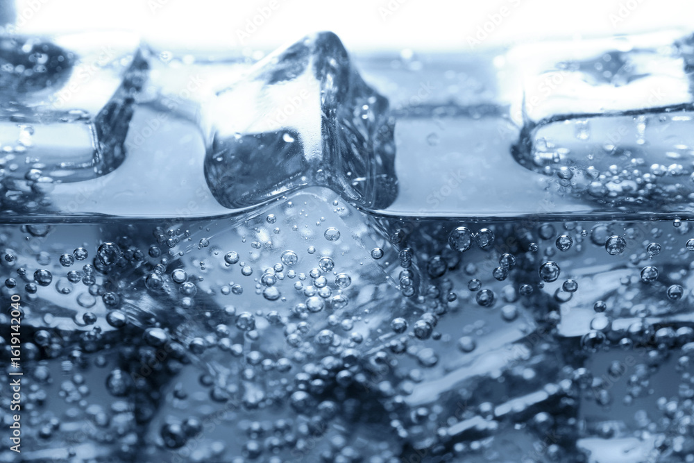 Soda water with bubbles and ice cubes in glass, closeup Soda water with bubbles and ice cubes in glass, closeup