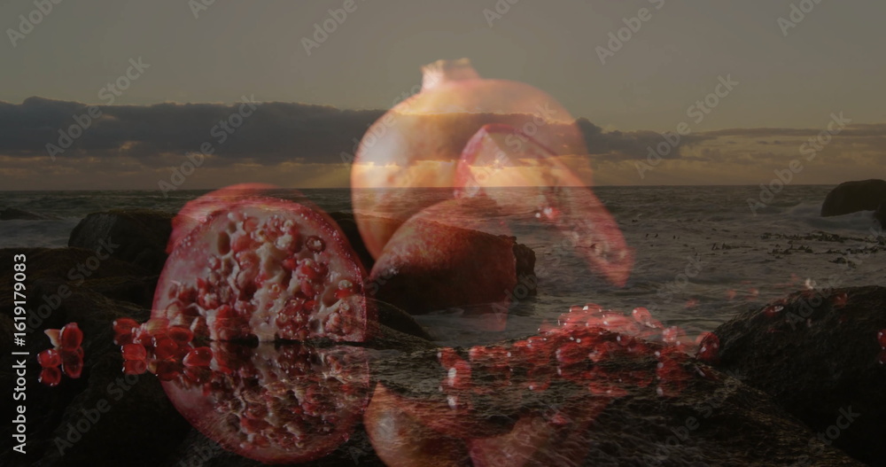 Obraz premium Blending whole and sliced pomegranate with rocky beach shoreline at sunset, revealing glossy arils