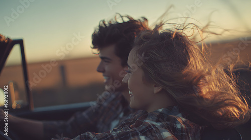 Romantic couple enjoying a vintage convertible ride with wind-blown hair during golden hour.