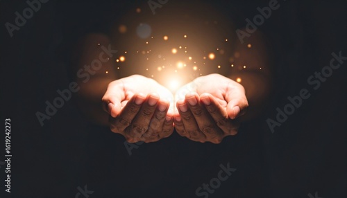 Two hands cupped together holding a bright light with sparkling particles, symbolizing hope, magic, or a precious gift in the darkness.