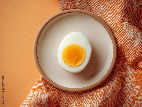 A boiled egg on a plate kept on an orage table.