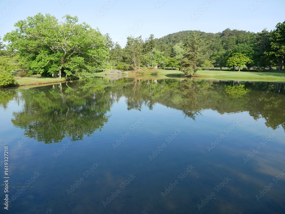 Fototapeta premium Tranquil Japanese Garden with Green Trees Reflected in a Pond on a Spring Morning, Iwate, Japan