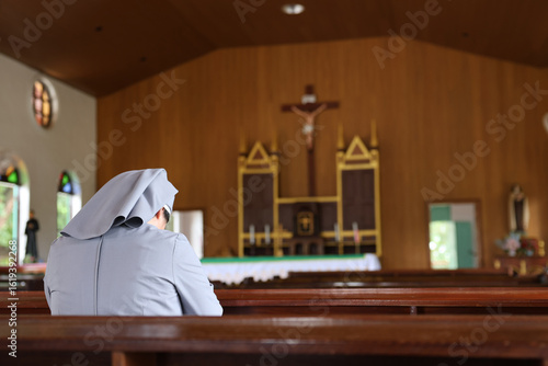 Christian nuns with white robes praying in a church.