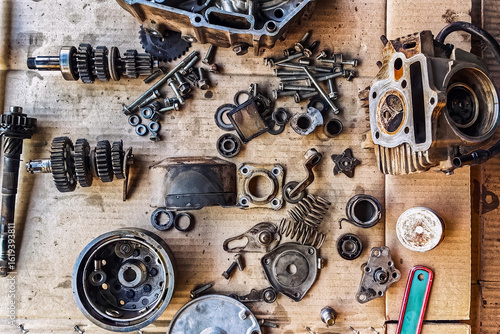Old parts of motorcycles background. Repair and maintenance old parts of engine. Old motorcycle spare parts on corrugated paper background. Disassembly of spare parts, gear, differential, engine, old.