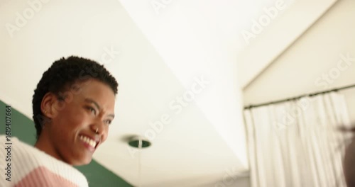 African American female friends sharing playful high-five after teasing near curtains and light