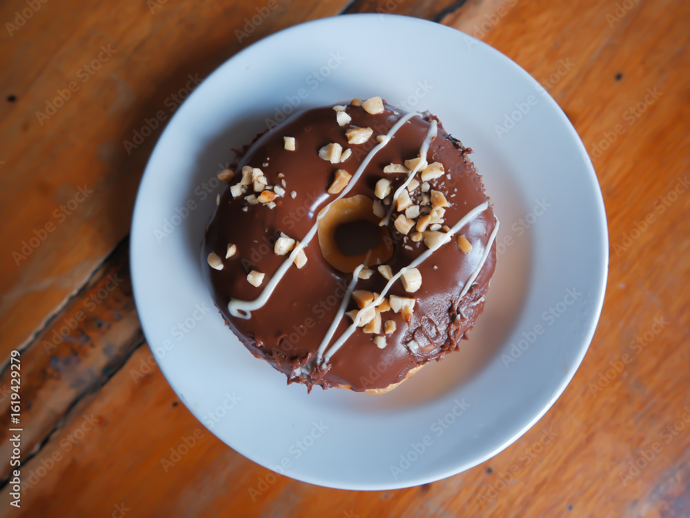Fototapeta premium Chocolate peanut flavor donut, served in a white plate, top view