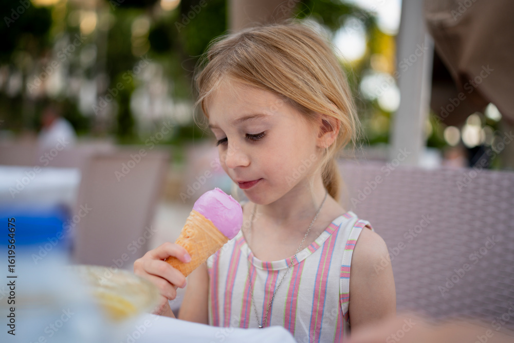 Child enjoying ice cream outdoors in summer wearing striped dress Child enjoying ice cream outdoors in summer wearing striped dress