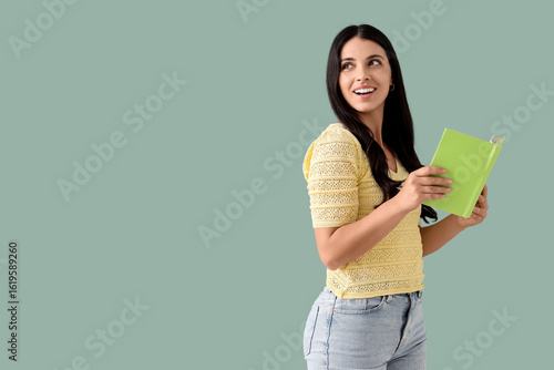 Beautiful woman with book on green background