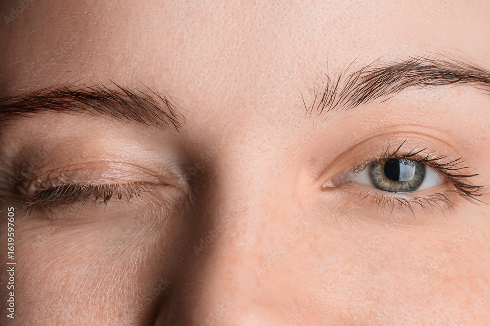 Obraz premium Winking woman with beautiful green eyes, closeup