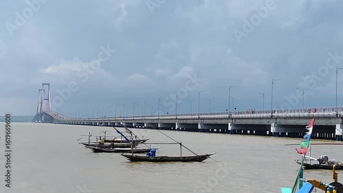 boat on the beach with the Suramadu bridge at the background