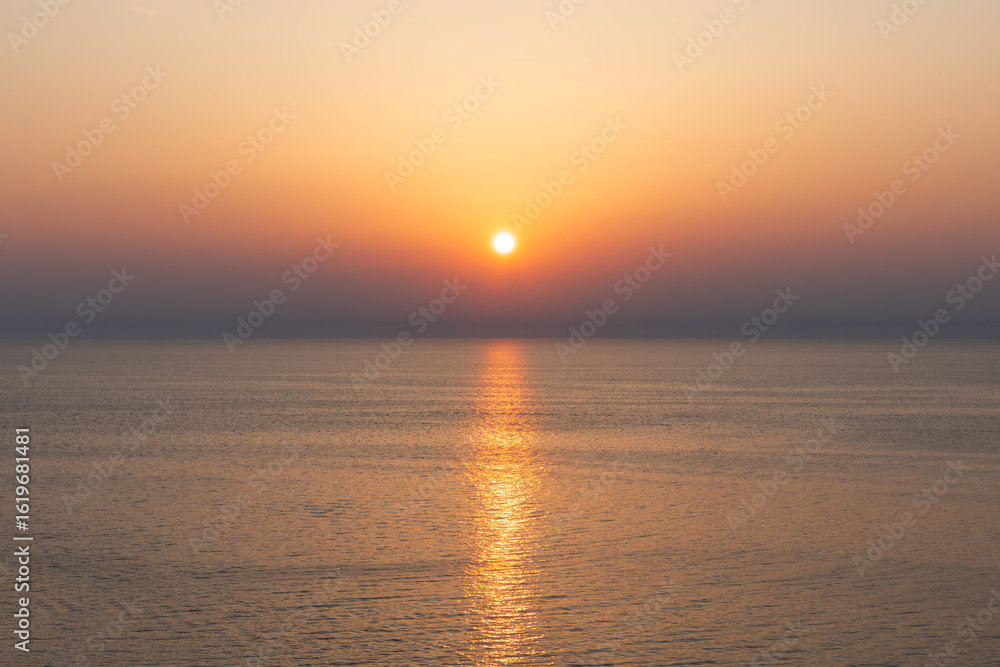Fototapeta premium clean seascape with calm sea water surface under soft sunset sky and sun reflection. sea under sunset in warm pastel