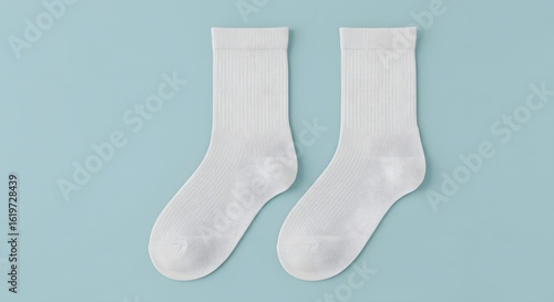 Two white crew socks isolated on a light blue background, flat lay composition. Minimalistic studio shot of clean, fresh, and simple socks, perfect for lifestyle, fashion, and product presentations.