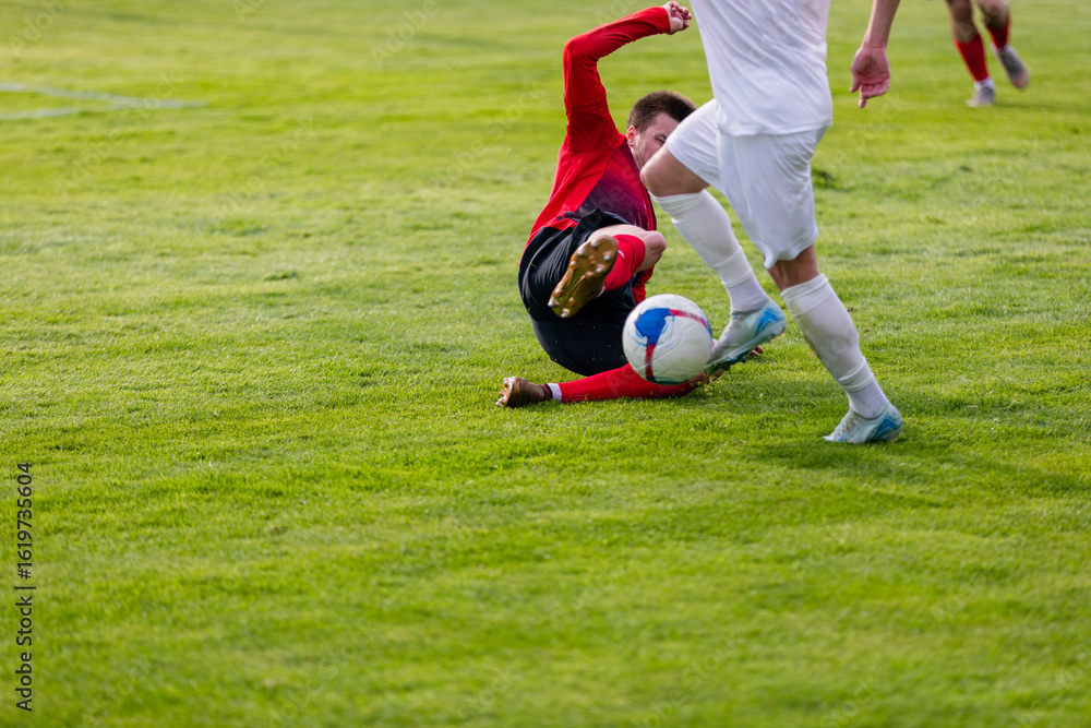 Obraz premium Athletes with a ball play football on the grass