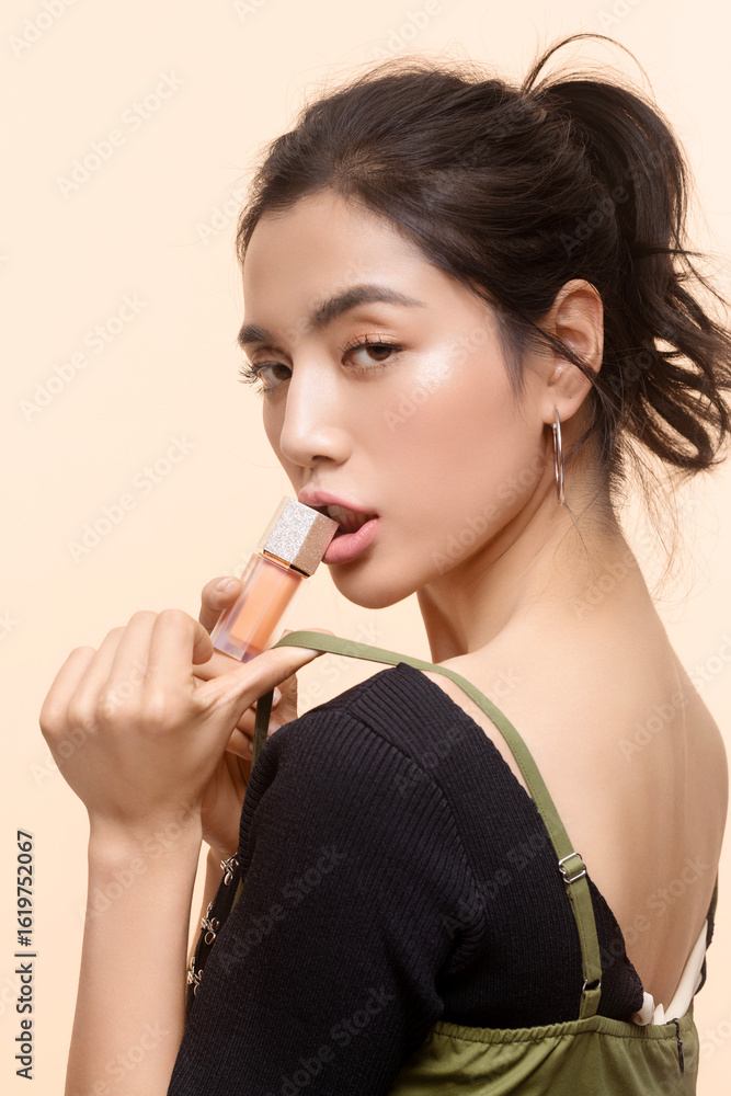Portrait of a young Asian woman holding cosmetic product. Portrait of a young Asian woman holding cosmetic product.