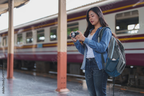 Young tourist taking photos at train station with backpack