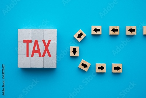 Fotografie Flat lay of arrow symbol block u-turn avoid TAX word block on blue background