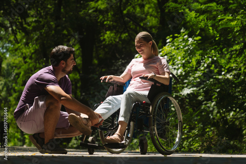 Man Assisting Woman in Wheelchair in a Peaceful Park
