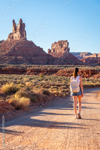 A woman is walking leisurely along a dirt road in the desert, Young Woman on Road in Valley of The Gods