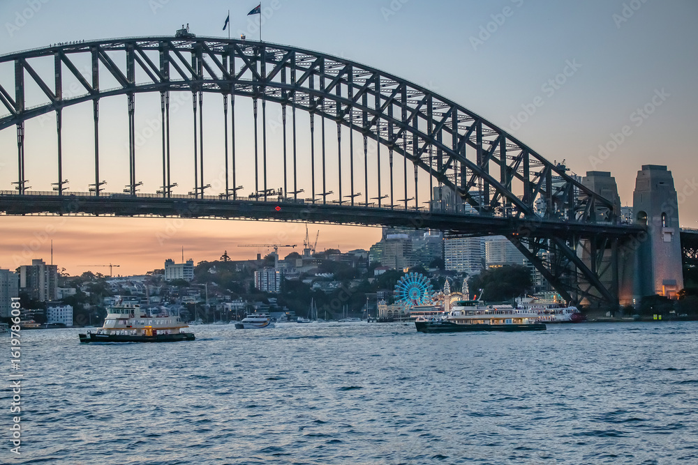 Obraz premium Sydney Harbour Bridge and Luna Park illuminated at dusk with city skyline behind