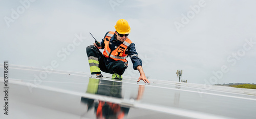 Tableau sur toile Worker inspects solar panels on a rooftop during daylight in a renewable energy