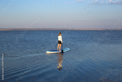 Woman on sup board. A beautiful young woman relaxes on a SUP board. Standup paddleboarding